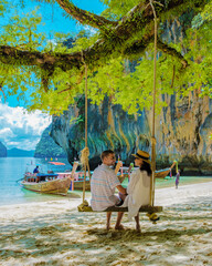 Koh Lao Lading near Koh Hong Krabi Thailand, Men and women on a beautiful beach with longtail boats, a couple of European men, and an Asian woman on the beach during vacation in Thailand