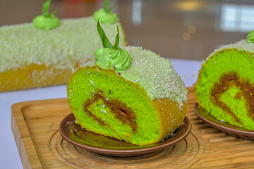 pandan BOLU cake with chocolate filling and coconut topping on wooden boards (in indonesia called kue bolu pandan)