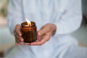 Woman in white clothes with mock up candle in jar in hands