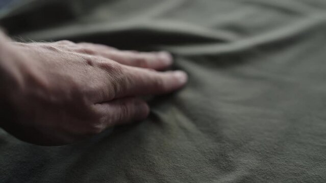 Slow motion handheld shot of man hand touching green cotton fabric