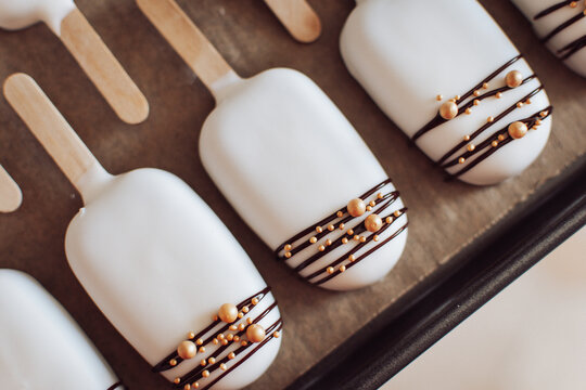 Cakesicles in wei&szlig; mit Schoko-Verzierung auf Blech