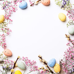 Overhead shot of Easter composition with spring flowers and colorful quail eggs over white background. Springtime and Easter holiday concept with copy space. Top view