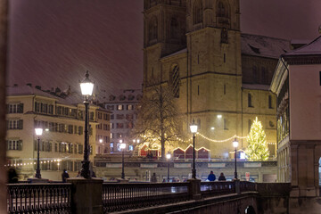 Old town of City of Zürich on a late autumn night with snowfall and Minster Bridge with Great...