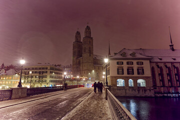 Fototapeta na wymiar Old town of City of Zürich on a late autumn night with snowfall and Minster Bridge with Great Minster church in the background. Photo taken December 10th, 2022, Zurich, Switzerland.