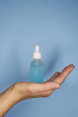 Female hands with serum in bottles on blue background