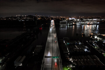 Night city street view, fast traffic, bridge over water, cars light streaks, transportation network, road.