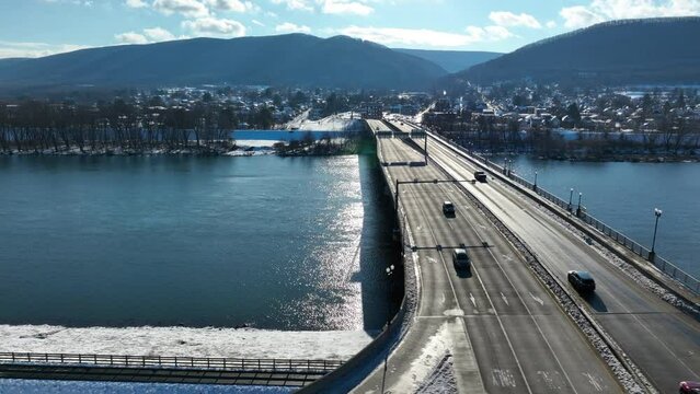 Aerial truck shot of cars driving on bridge over icy Susquehanna river in Williamsport PA. Snow day.