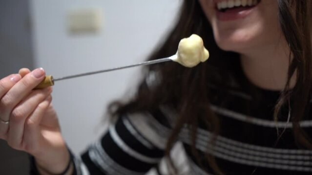 Young Cute Girl Eating Fondue, A Swiss Melted Cheese Dish Served In A Communal Pot  Over A Portable Stove Heated With A Candle And Eaten By Dipping Bread Into The Cheese Using Long Forks.