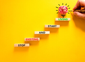 Stop existing start living symbol. Concept words Stop existing and start living on wooden blocks....