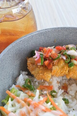 chicken katsu sambal matah with salad and sunny side up egg and drinks on a wooden table.