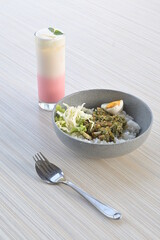 green chili squid rice with salad and pink lava drink on wooden table or in indonesia called nasi cumi cabe ijo (natural light)