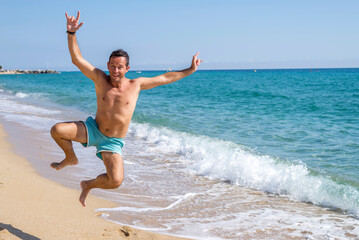 Front view of man in swimsuit jumping on seashore at beach sunny day