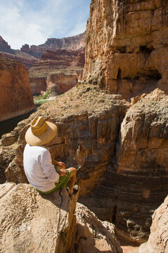 A man sits high on the rim of South Canyon, part of the Grand Canyon in Arizona.