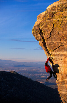 Climber climbing a wall in nice light against a blue sky.