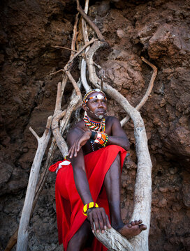 Portrait of a traditional Maasai guide standing on a makeshift wooden ladder.