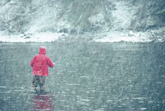 A fly-fisherman casts his line in a snowstorm.