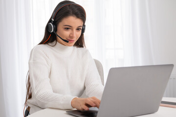 A young beautiful woman with headphones is engaged in online education. Teaching online concept  - obrazy, fototapety, plakaty