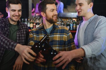 Friends having fun. Happy young men in casual wear drinking beer in pub.