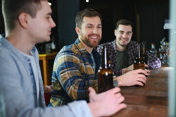 Friends resting in the pub with beer in hands. Having conversation.