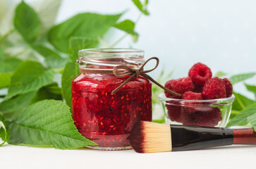 Raspberry mask (scrub) in a small glass jar and make-up brush. Homemade face or eye mask, natural beauty treatment and spa recipe. Copy space.
