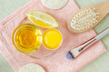 Olive oil, lemon slice, egg yolk, wooden hairbrush and make-up brush. Natural skin and hair care, homemade spa and beauty treatment recipe. Top view.