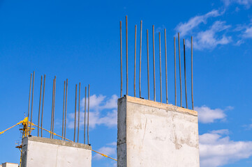 The foundation on reinforced concrete piles and the frame during the construction of a multi-storey building. Reinforcement of reinforced concrete columns. Iron fittings in concrete piles.