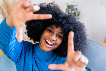 Cheerful black girl showing sign of a camera frame