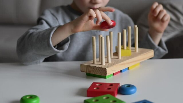 Child plays with figurines from wooden toys. Montessori games for child development. The concept of games, learning and early development of the child. Children's wooden toy.Fine motor skills of hands