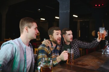 Soccer fans at the bar. Happy football fans cheering at bar and drinking beer while bartender serving beer at the background