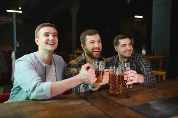 Soccer fans at the bar. Happy football fans cheering at bar and drinking beer while bartender serving beer at the background