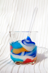 Various toothpaste of many colors squeezed into a cup with a spoon. Delicious colorful toothpaste as a dessert concept