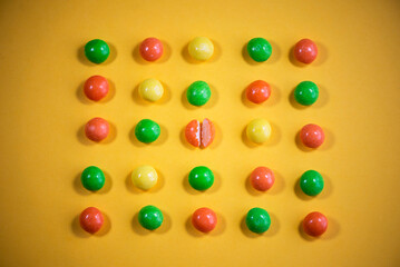 multi-colored dragee in rows on a yellow background
