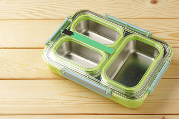 Metal lunch box with compartments on wooden background
