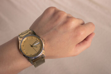 Classic Gold Watch on wrist. Woman watching watch in wrist watch on a light background. First-person view (FPV), first-person point of view (POV)