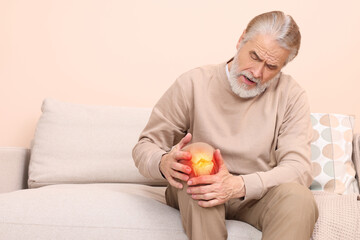 Arthritis symptoms. Senior man suffering from pain in his knee at home, space for text