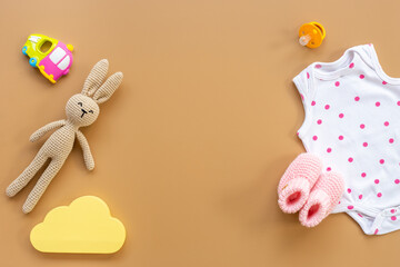 Newborn baby bodysuit with rabbit toy, flat lay, top view