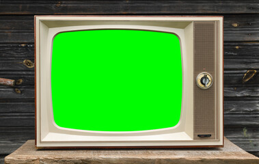 Old vintage TV with green screen on wooden wall background.