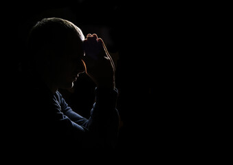 Young man praying on dark background