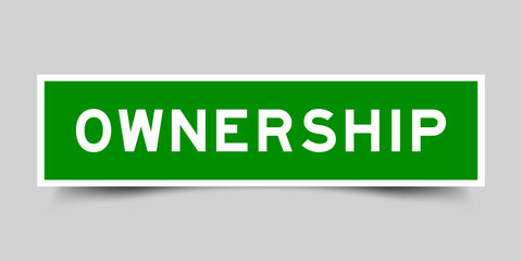 Green color square label sticker with word ownership on gray background