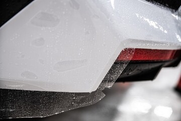 Colorless protective film covering the paintwork of a white car. The film protects the car paint...