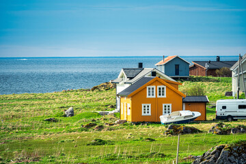 Fototapeta na wymiar Photograph of typical Norwegian colored houses at Rambergstranda beach in Lofoten, Norway, during spring on a clear day with clouds