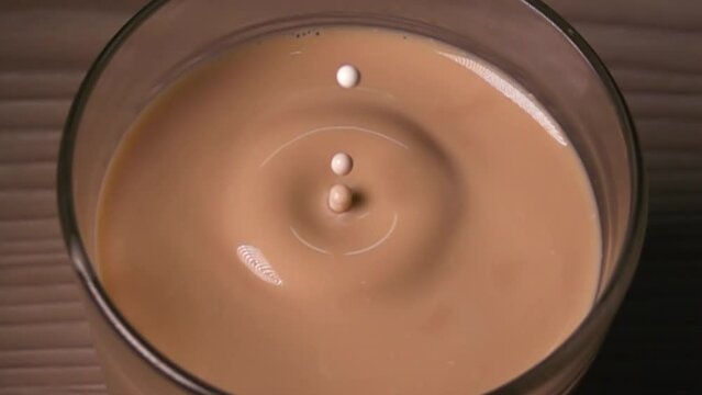 A drop of milk falls into a cup of coffee in super slow motion
