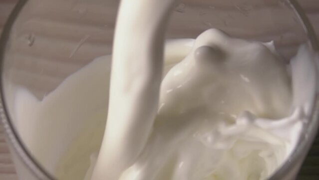Milk is poured into a transparent glass in super slow motion