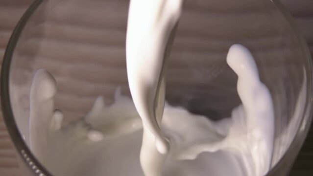 Close-up of a person pouring milk in slow motion with corona splash.