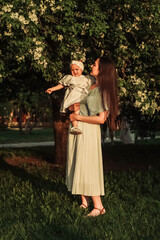 Mother and little daughter near blooming apple tree.