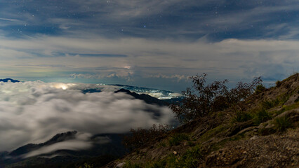 Night at the top of the Agung volcano. Panoramic view of East Java and Bali against the background of clouds. The background of the natural landscape. Bali Island, Indonesia