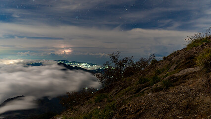 Night at the top of the Agung volcano. Panoramic view of East Java and Bali against the background of clouds. The background of the natural landscape. Bali Island, Indonesia