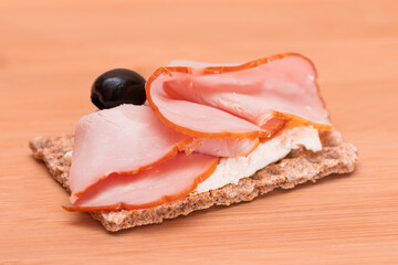 Whole Grain Crispbread with Ham, Cream Cheese and Olives on Bamboo Cutting Board. Easy Breakfast....