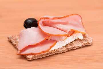 Whole Grain Crispbread with Ham, Cream Cheese and Olives on Bamboo Cutting Board. Easy Breakfast. Diet Food. Quick and Healthy Sandwiches. Crispbread with Tasty Filling. Healthy Dietary Snack