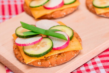 Light Breakfast. Quick and Healthy Sandwich. Fresh Cucumber and Radish with Green Onions and Cheese on Crispy Cracker on Wooden Cutting Board